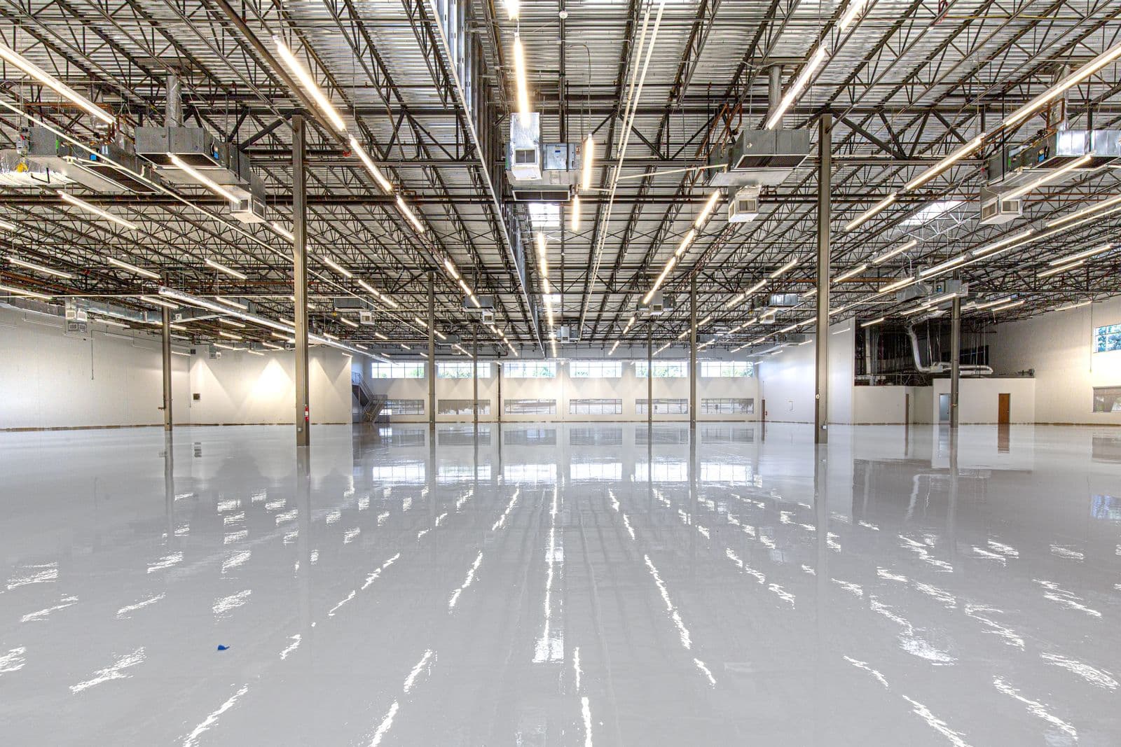 Gloss epoxy floor finish reflecting overhead lighting in a large facility